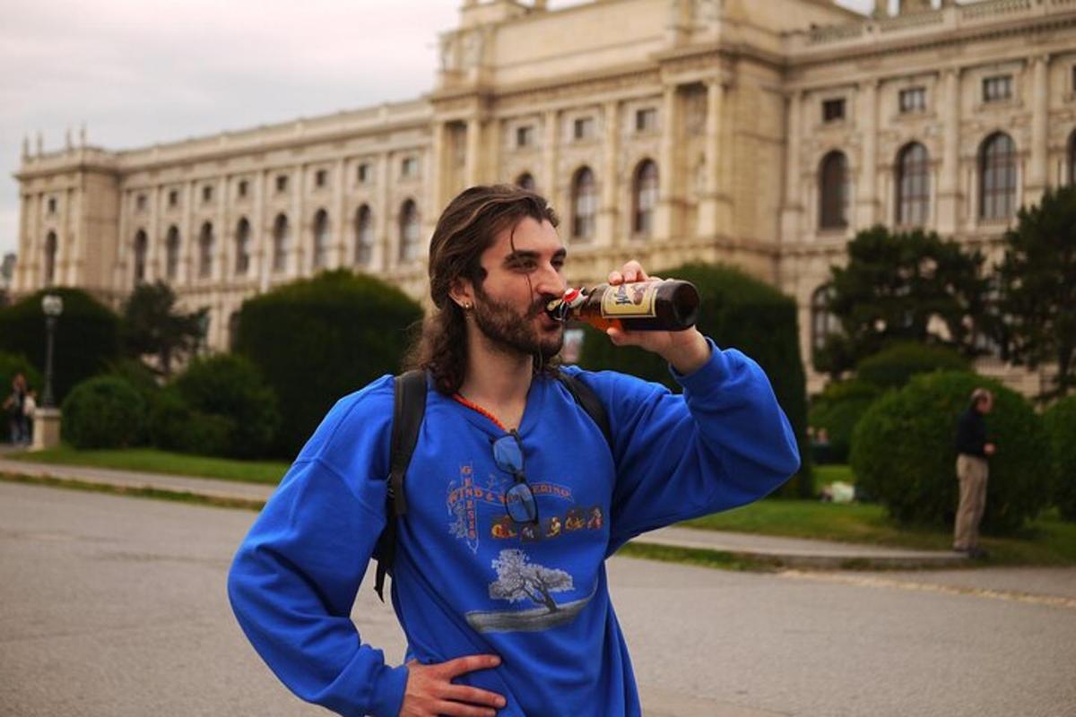 muž pije drink z lahve před budovou
