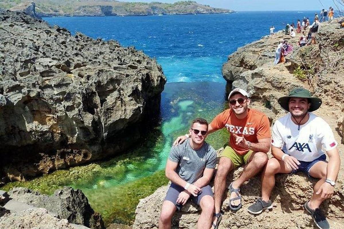 tres homes asseguts en unes roques prop de l'oceà