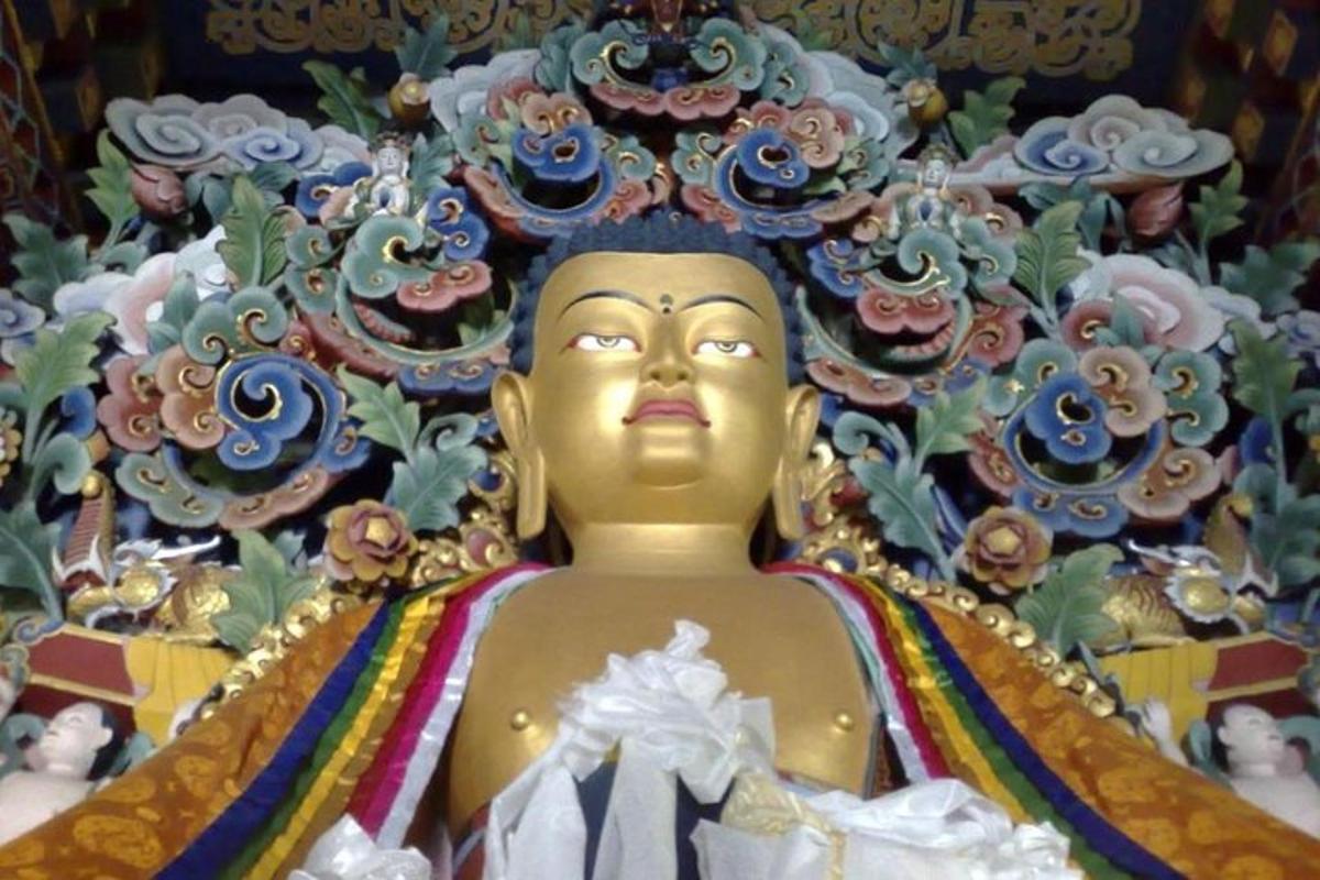 isang gintong buddha statue sa harap ng isang painting