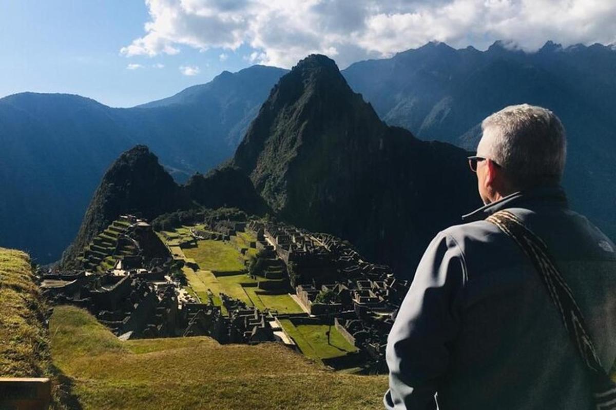 um homem em pé no topo de uma montanha com vista para uma cidade