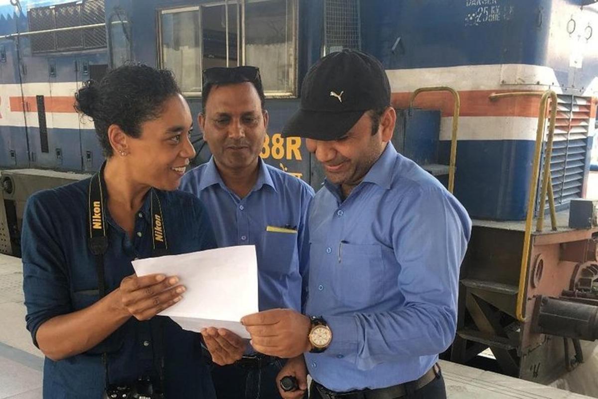 Tres hombres y una mujer de pie junto a un tren