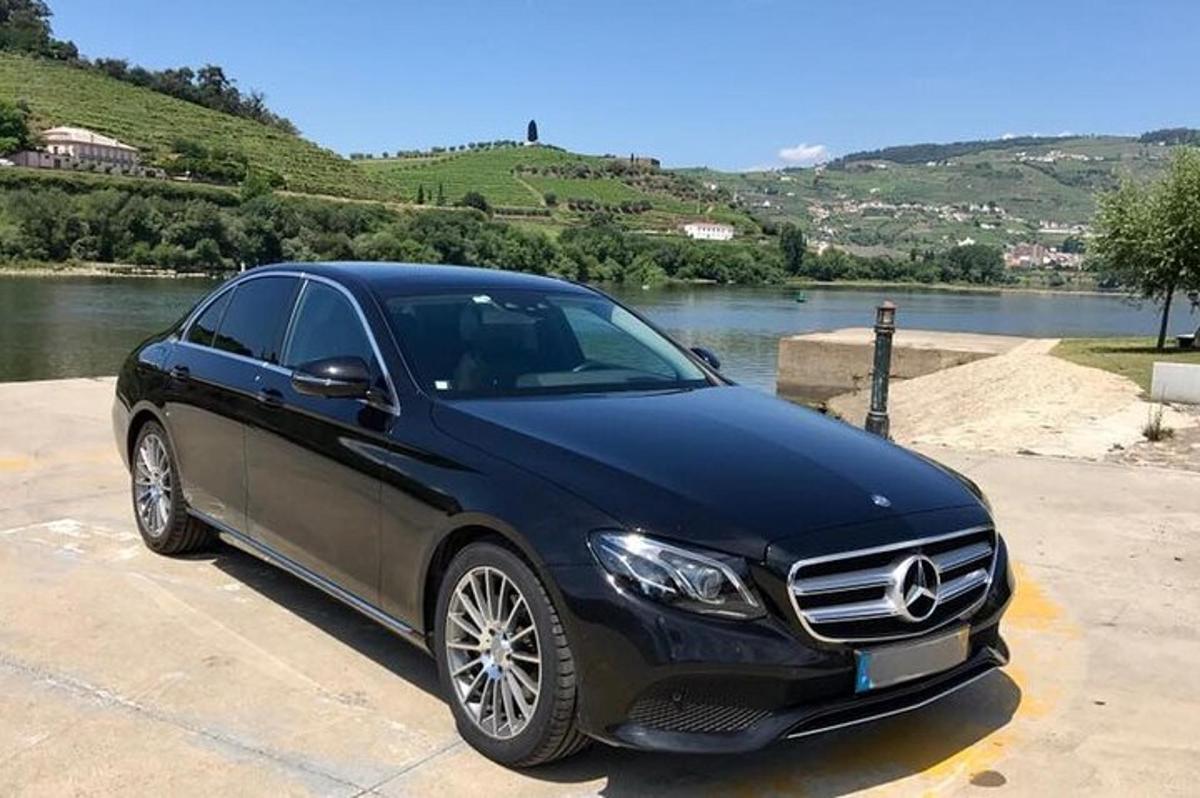 une voiture noire garée sur un parking à côté d'une rivière