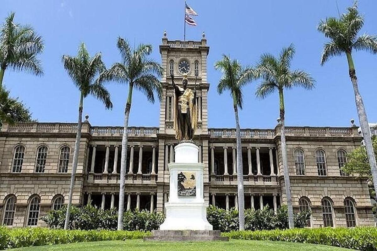 un edificio con una torre dell'orologio e una statua di fronte