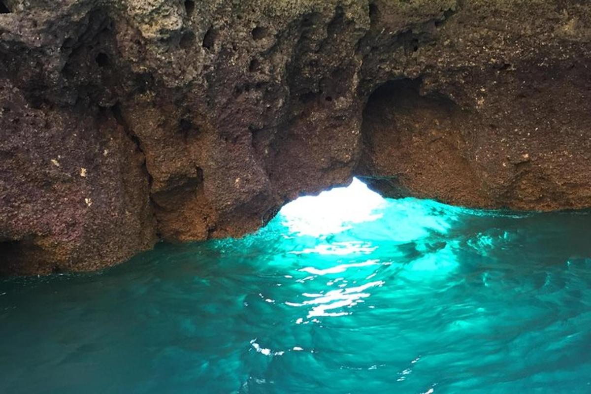 una grotta rocciosa con acqua blu di fronte
