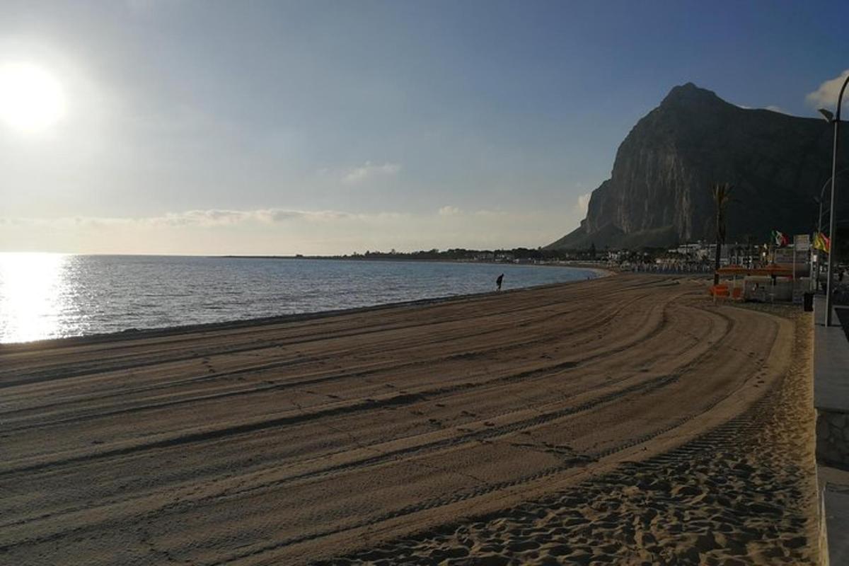 egy strand, ahol egy ember sétál a homokon