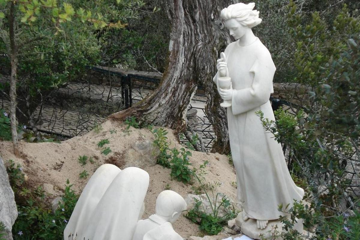 una estatua de una mujer parada junto a un árbol