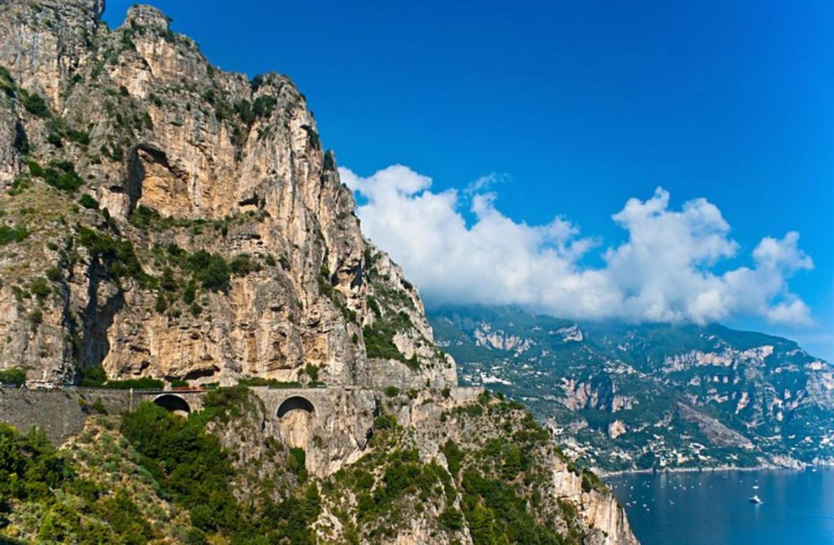 una montagna con una strada accanto all'acqua