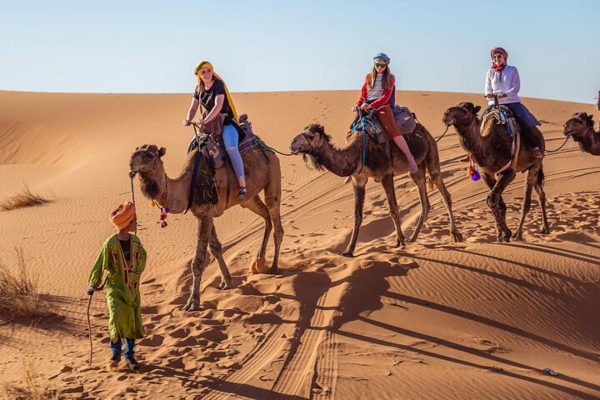 un gruppo di persone a cavallo di cammelli nel deserto