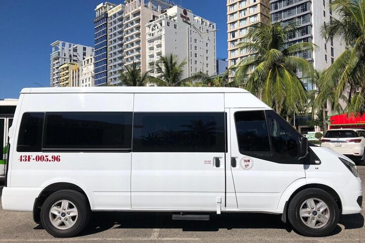 bel kombi parkiran na parkirišču z visokimi stavbami