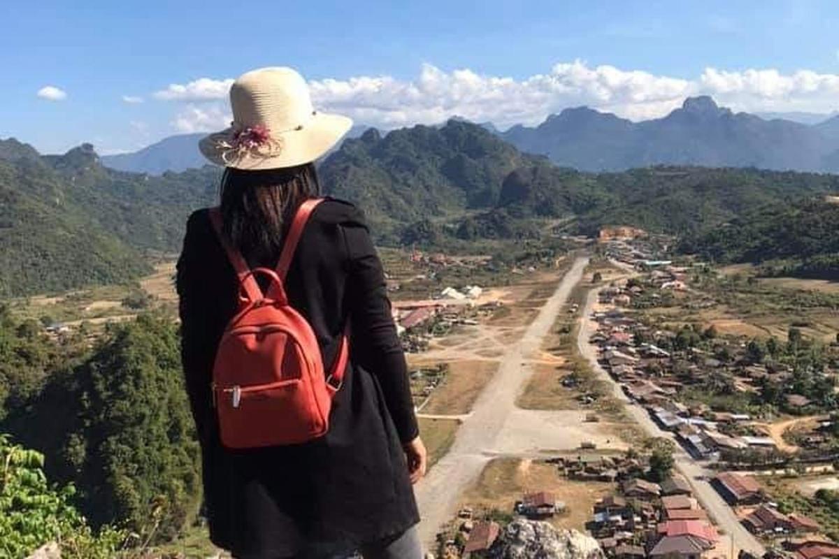 a woman with a red backpack standing on top of a mountain