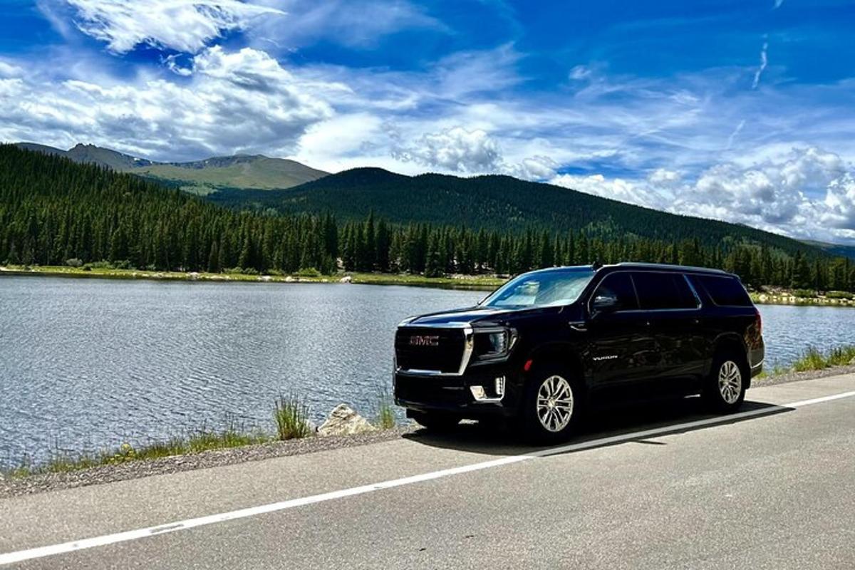 a black truck parked on a road next to a lake