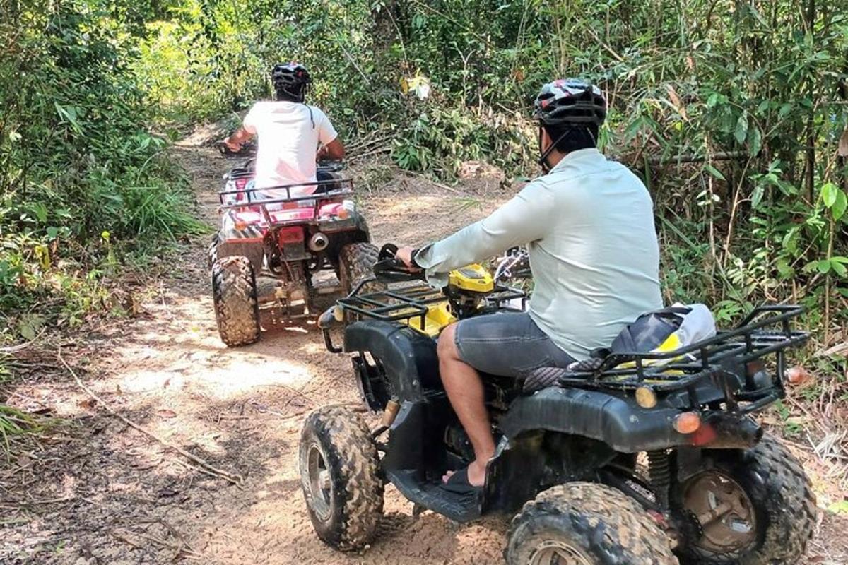 两个人骑着四轮摩托车在泥路上行驶