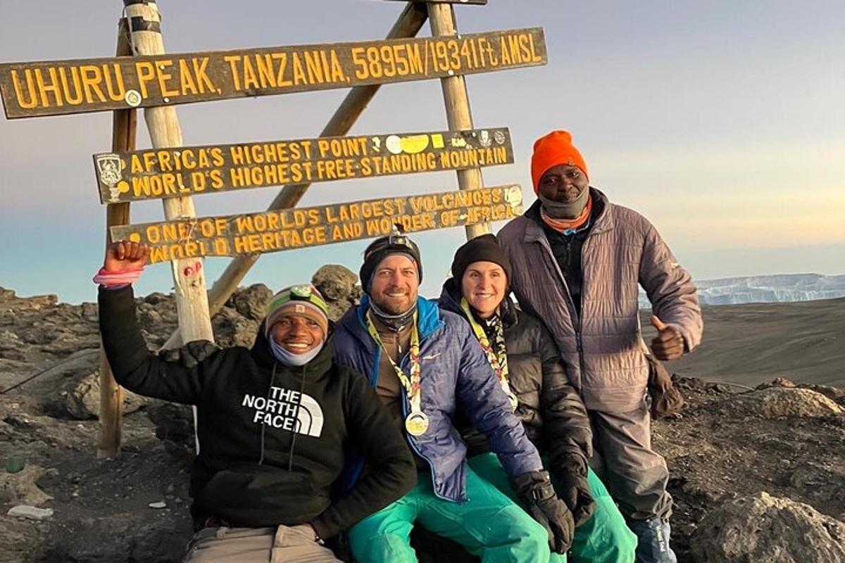 sekelompok orang berdiri di samping tanda di gunung