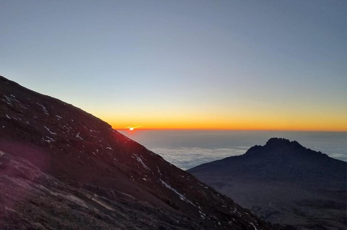 o priveliște a apusului de soare din vârful unui munte