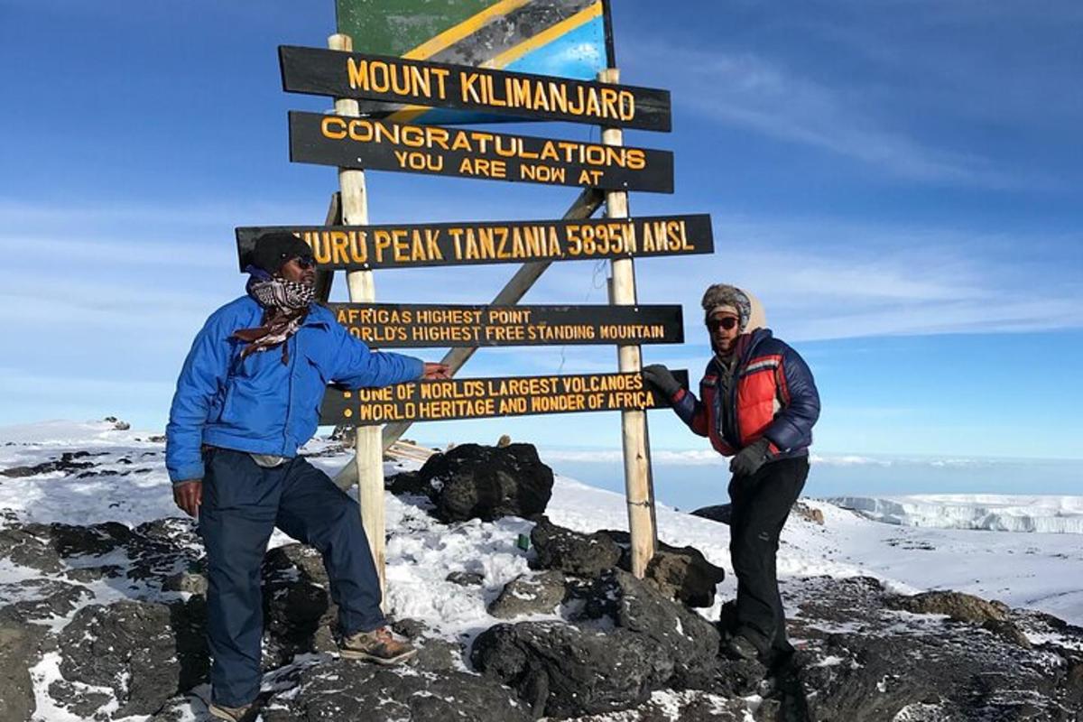 due persone in piedi accanto a un cartello su una montagna