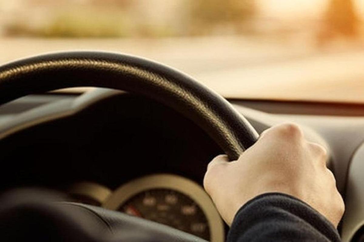 osoba řídící auto s rukama na volantu