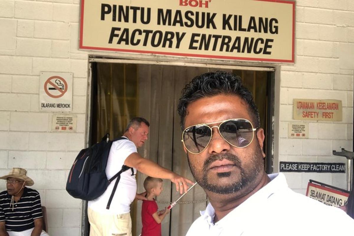 un uomo con occhiali da sole in piedi fuori dall'ingresso di una fabbrica