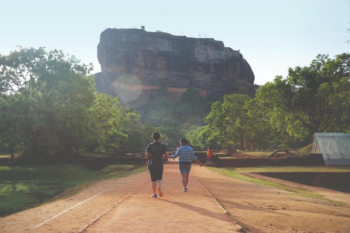 dues persones caminant per un camí de terra a prop d'una formació rocosa