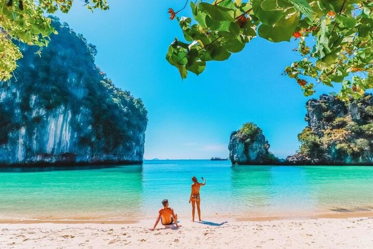 dva človeka stojita na plaži pred oceanom