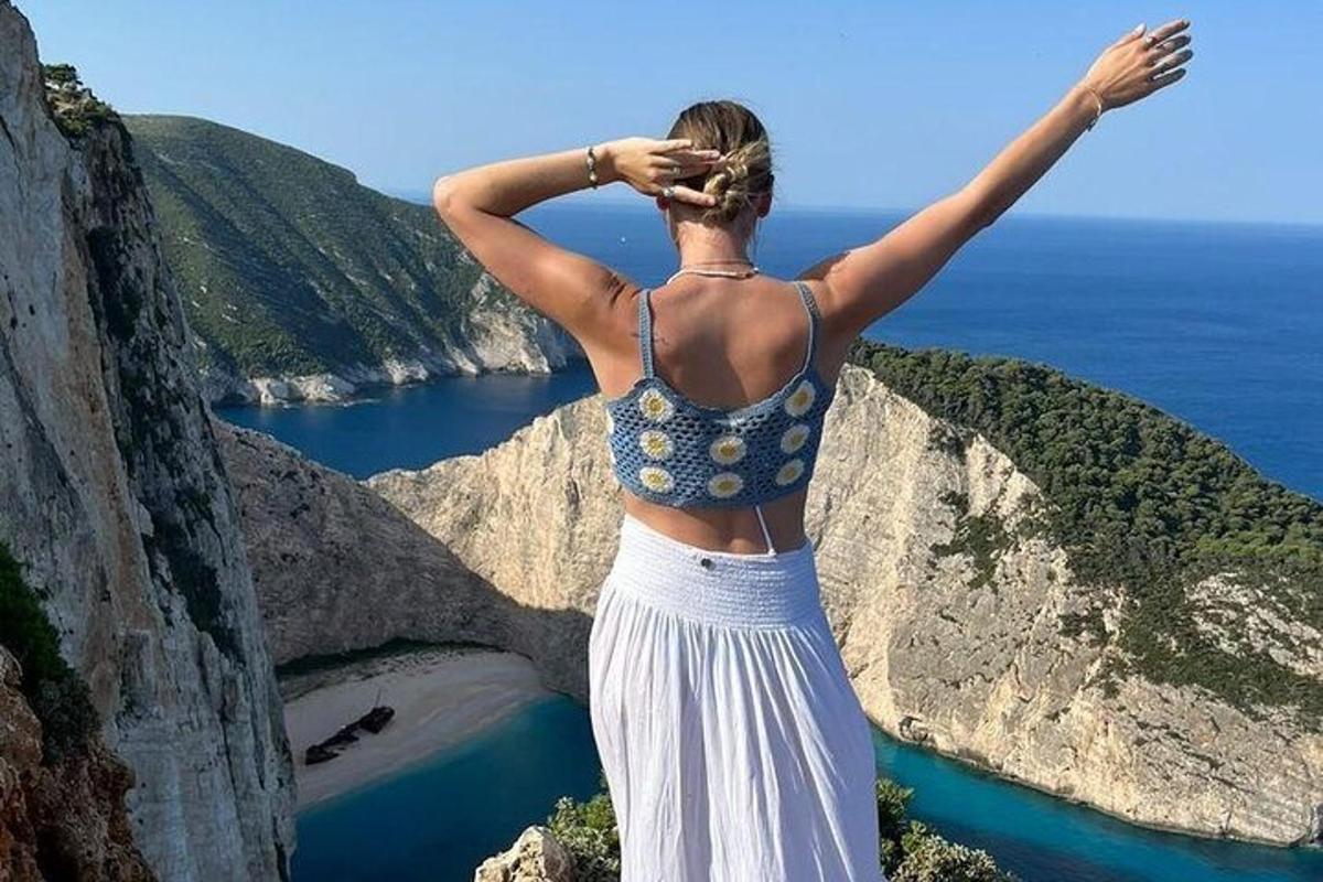 žena stojící na útesu s rozpaženýma rukama