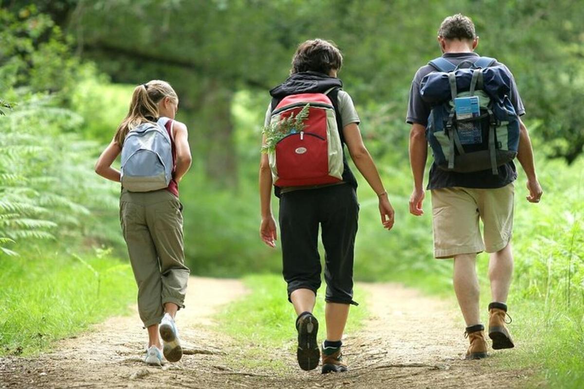 a group of three people walking down a trail with backpacks