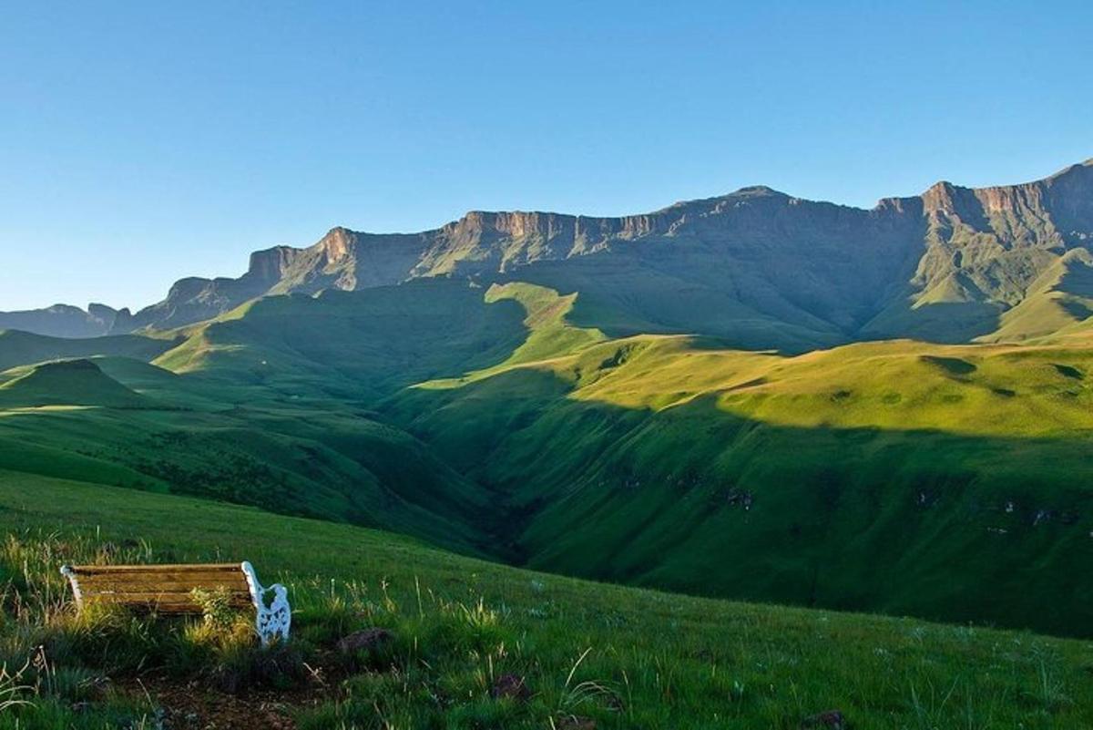 um banco em uma colina com montanhas ao fundo