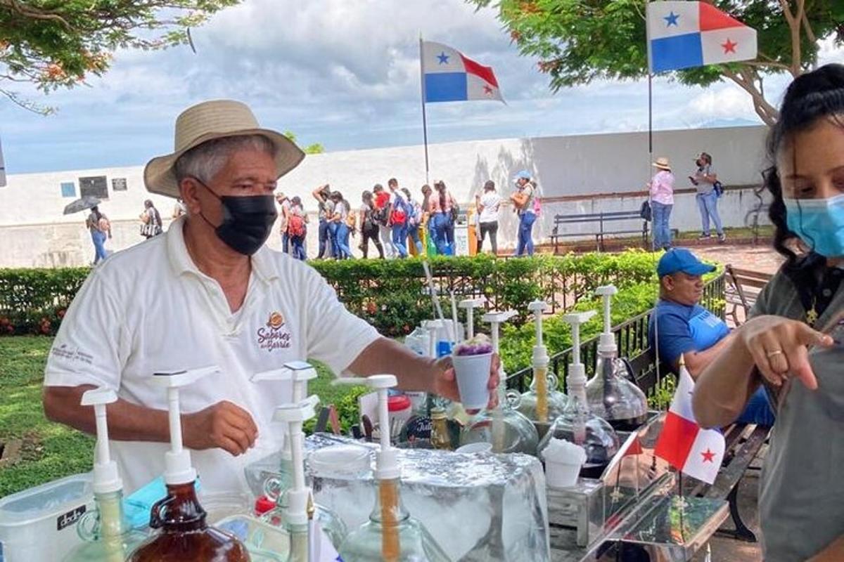 Un hombre con mascarilla en una mesa llena de botellas.