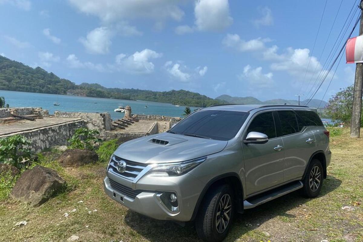 um SUV prateado estacionado em uma colina ao lado de um lago