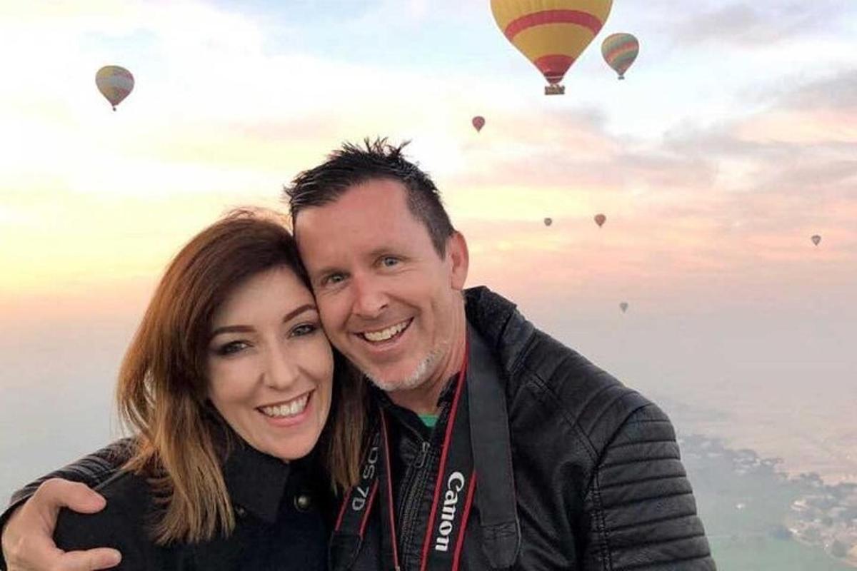 Un hombre y una mujer posando para una foto con globos aerostáticos.