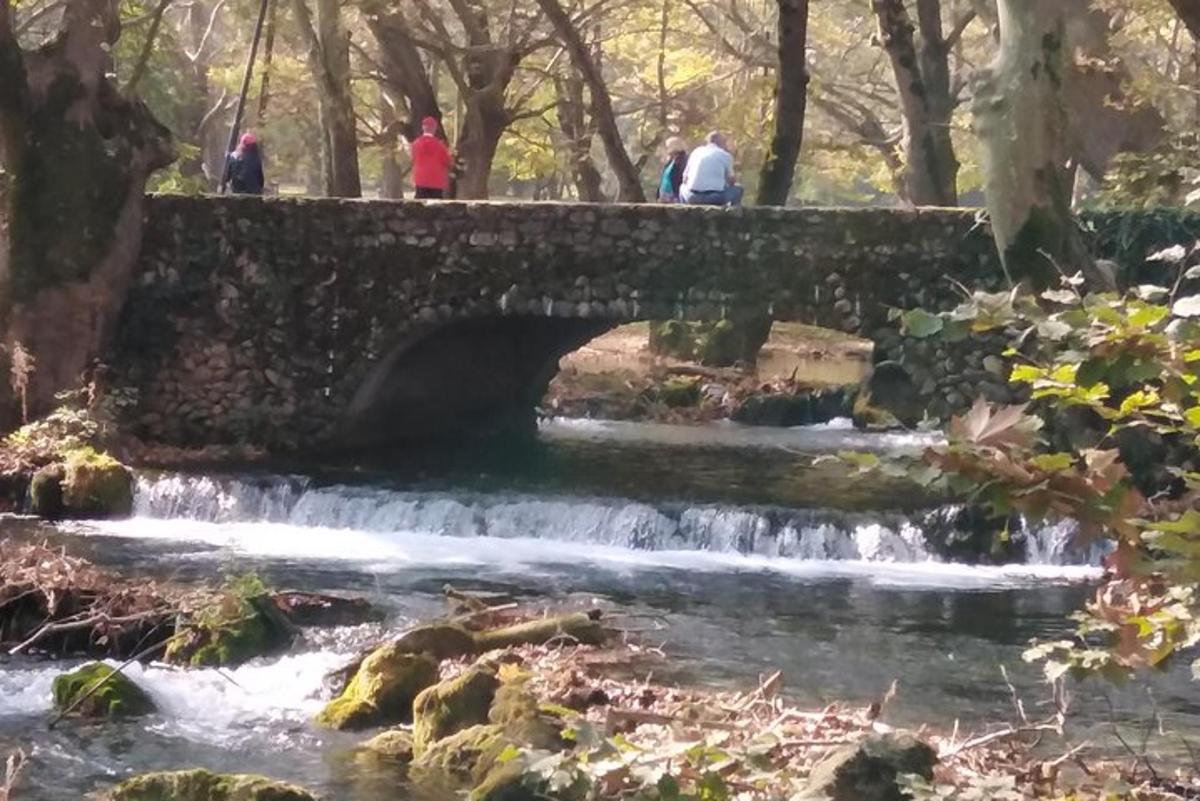 ljudje hodijo čez kamniti most čez potok