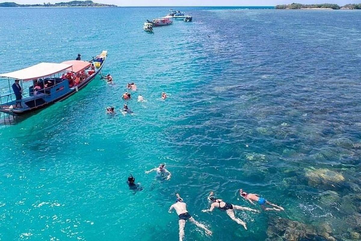 un gruppo di persone che nuotano nell'acqua accanto a una barca