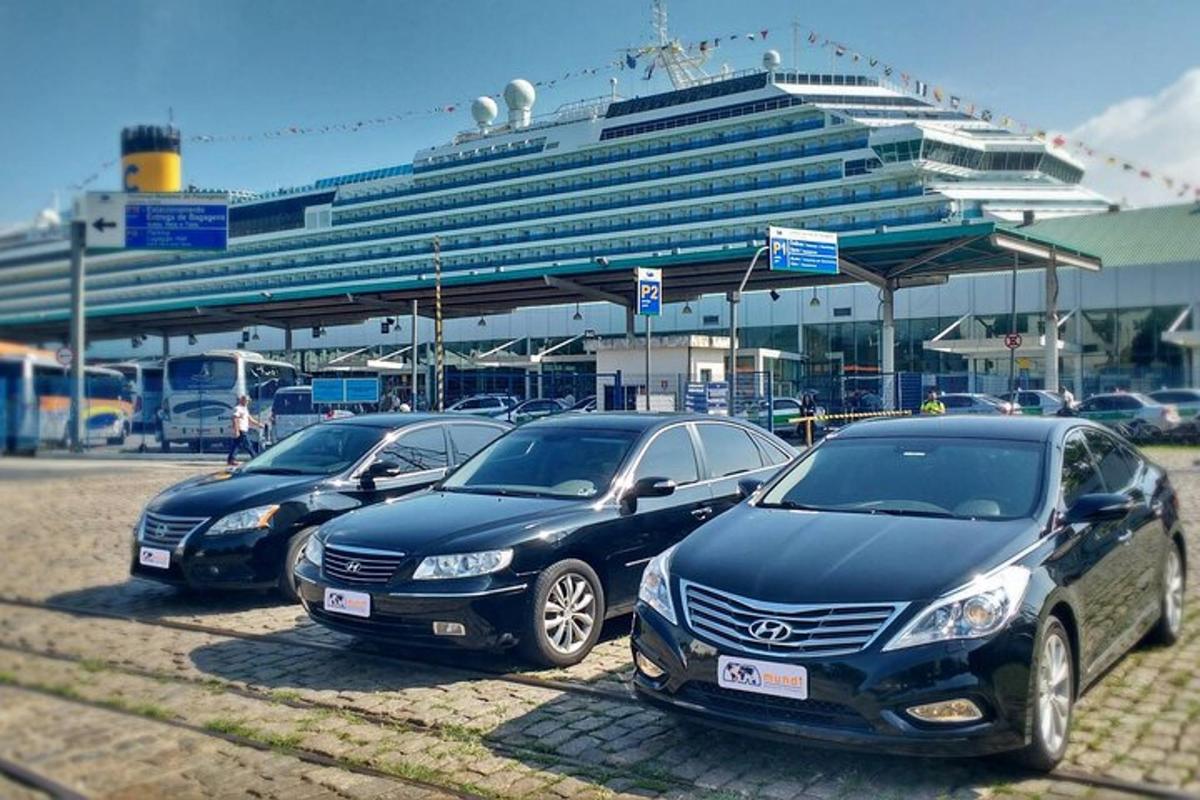 a row of parked cars in front of a cruise ship