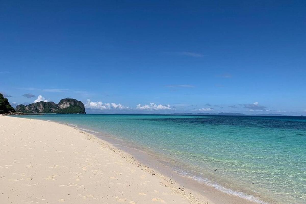 pantai dengan air biru dan bebatuan di latar belakang
