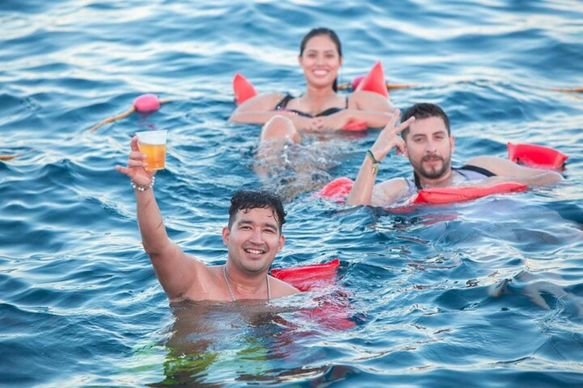 tres persones a l'aigua amb un got de cervesa