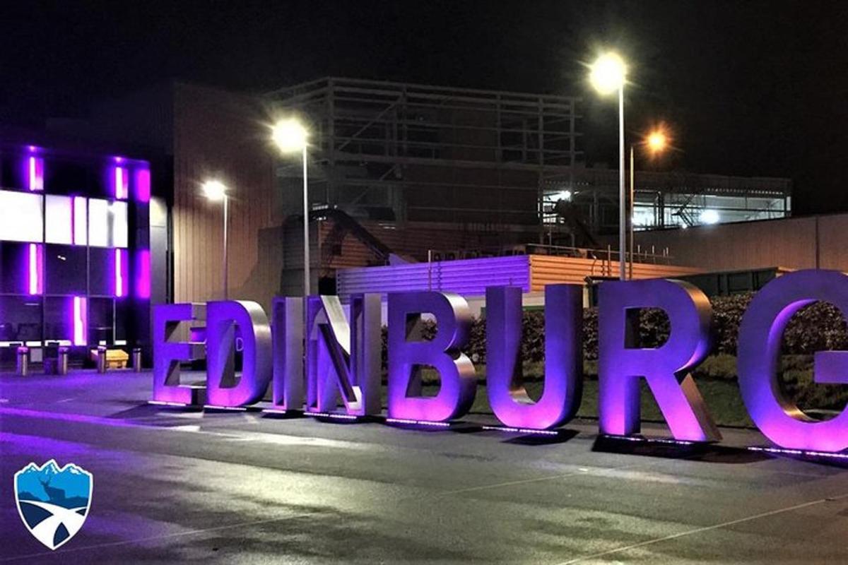 a large purple sign on a street at night