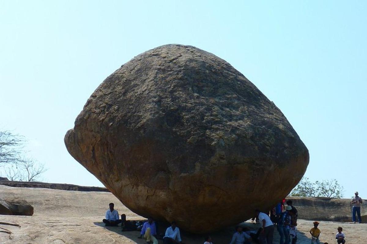 a group of people standing around a large rock