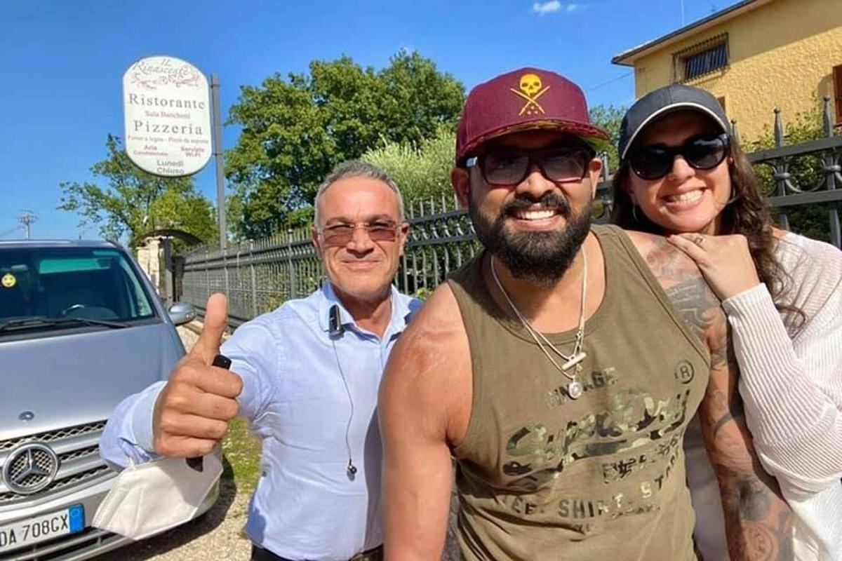 tre persone posano per una foto con un'auto