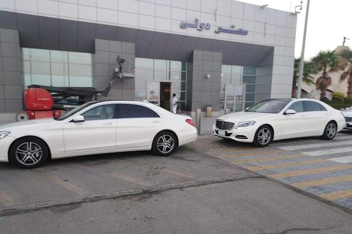 hai chiếc xe màu trắng đậu trước một tòa nhà