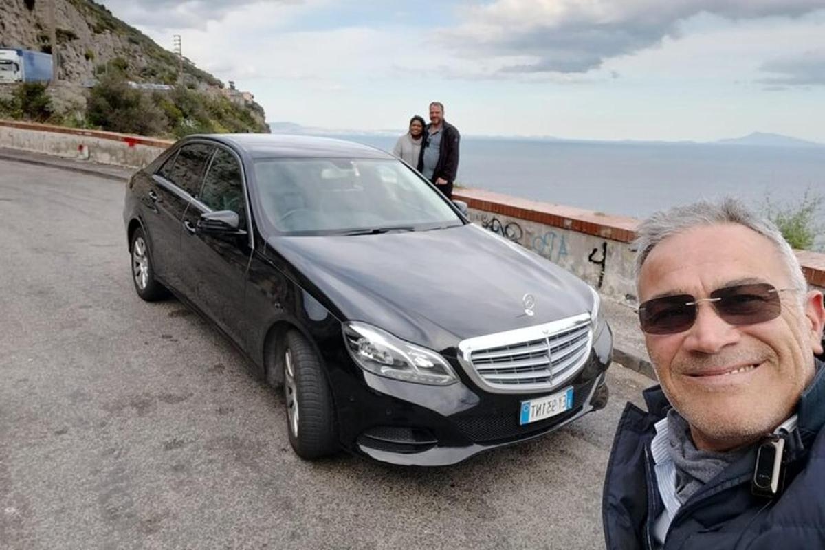 un uomo in piedi accanto a un'auto nera su una strada