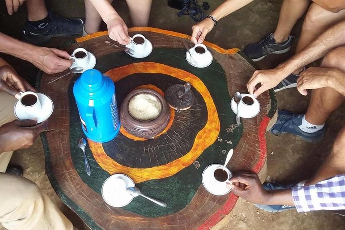 een groep mensen die rond een tafel zitten met kopjes