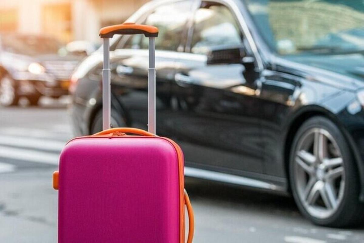 a pink suitcase sitting in front of a car