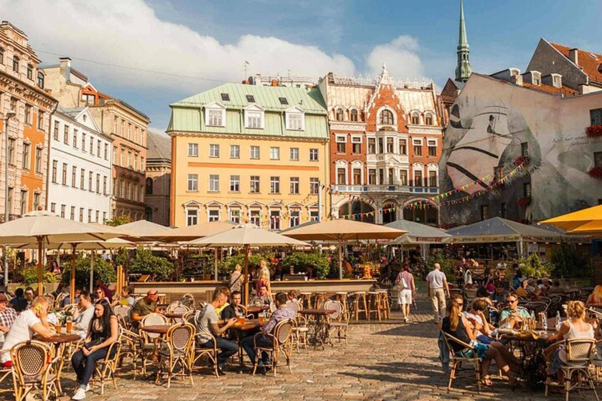 a group of people sitting at tables in a street with buildings