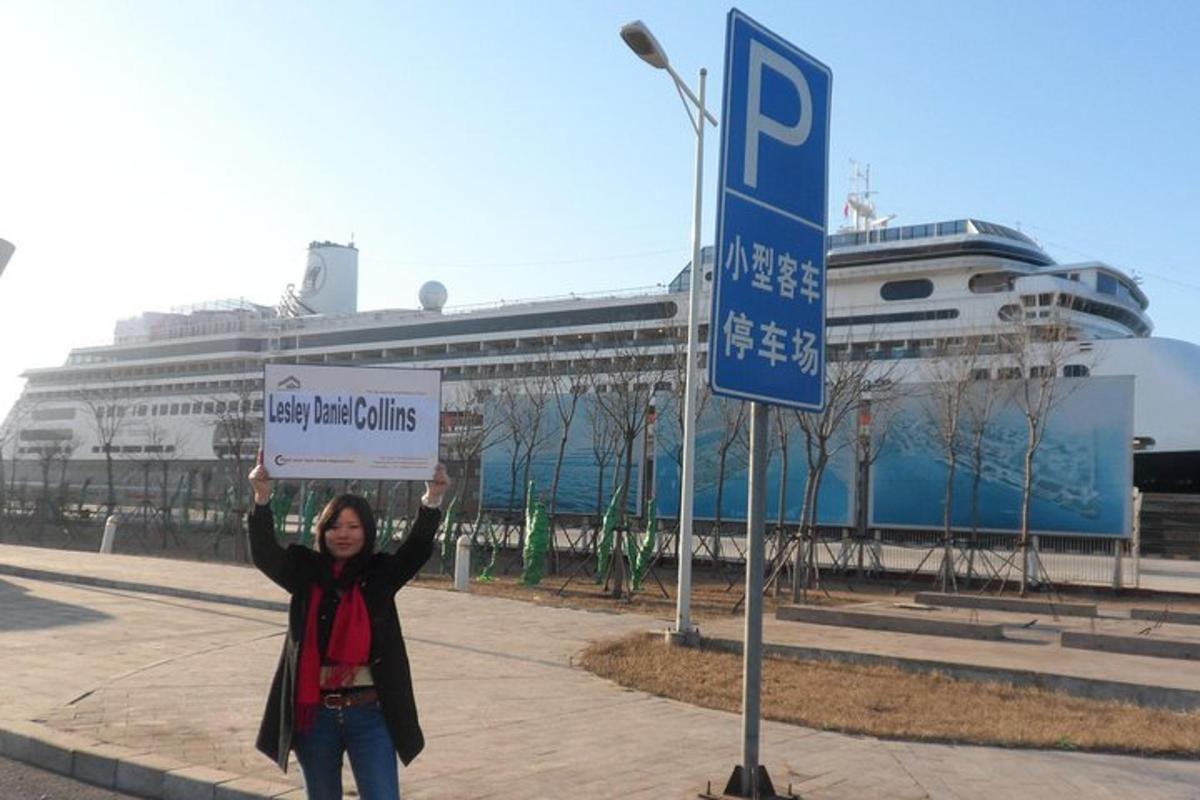a woman holding up a sign in front of a cruise ship