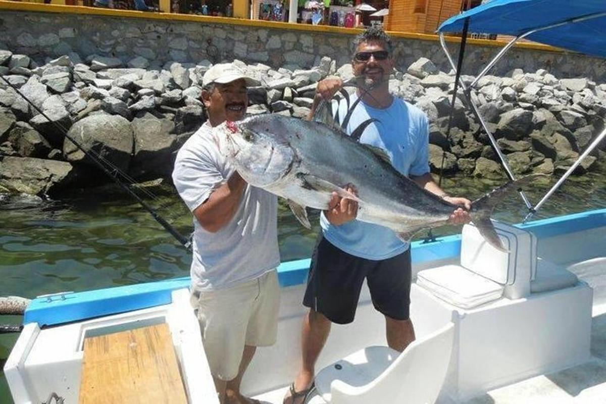 due uomini su una barca che tengono in mano un grosso pesce