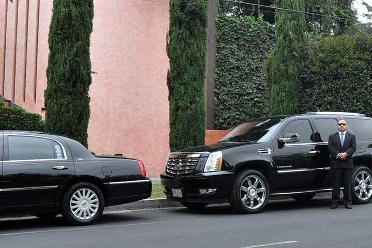 muž v obleku stojící vedle černého SUV