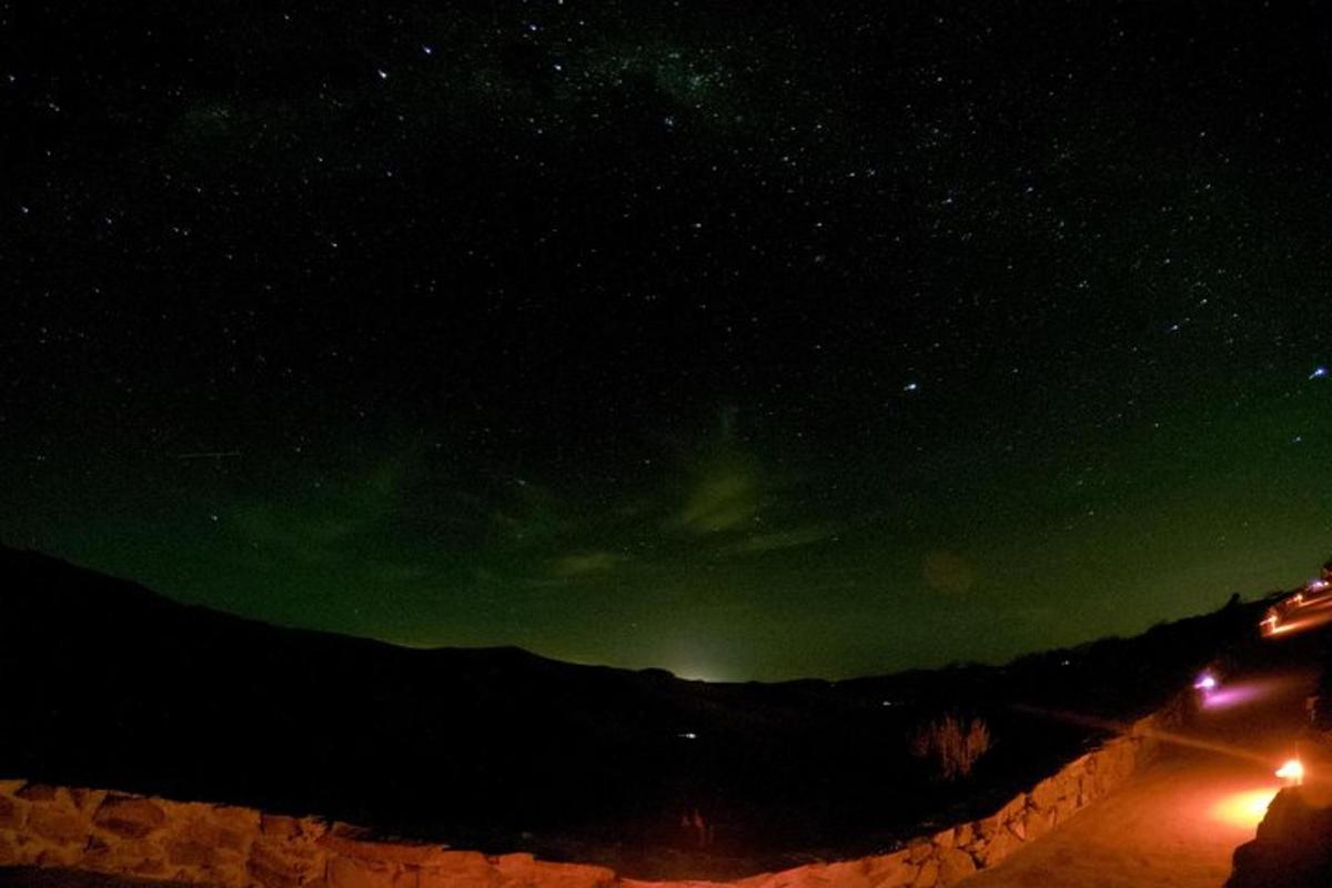 a starry night with a green sky and a wall