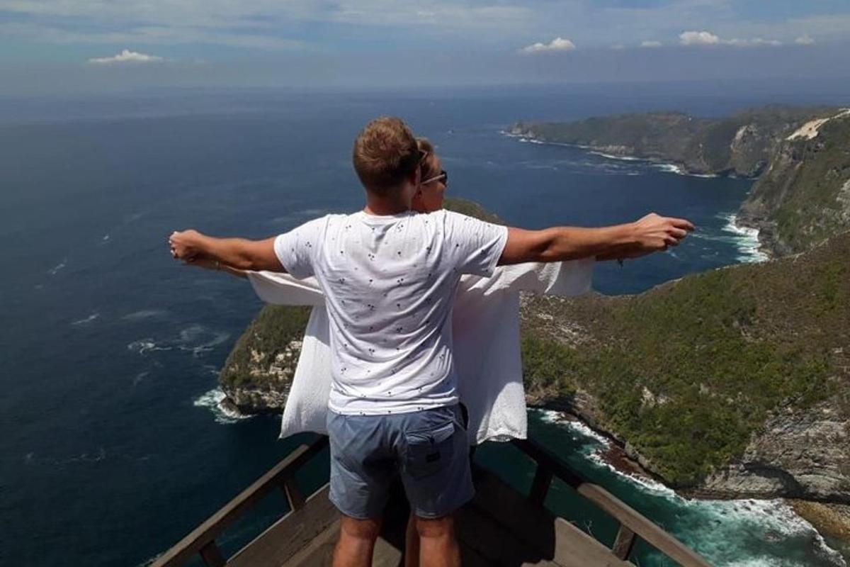 muž stojící na vrcholu hory s rozpaženýma rukama