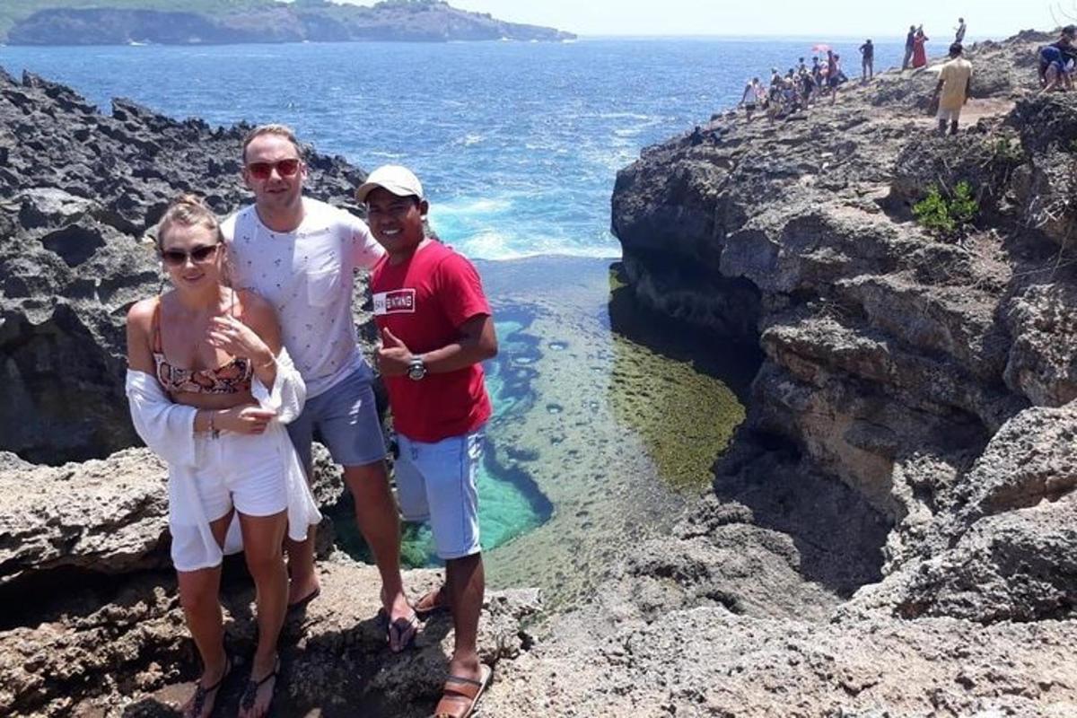 tři lidé stojící na skalách poblíž oceánu
