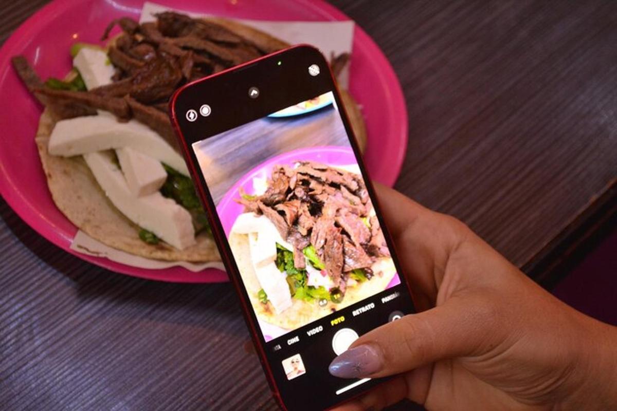 a person holding a cell phone in front of a plate of food