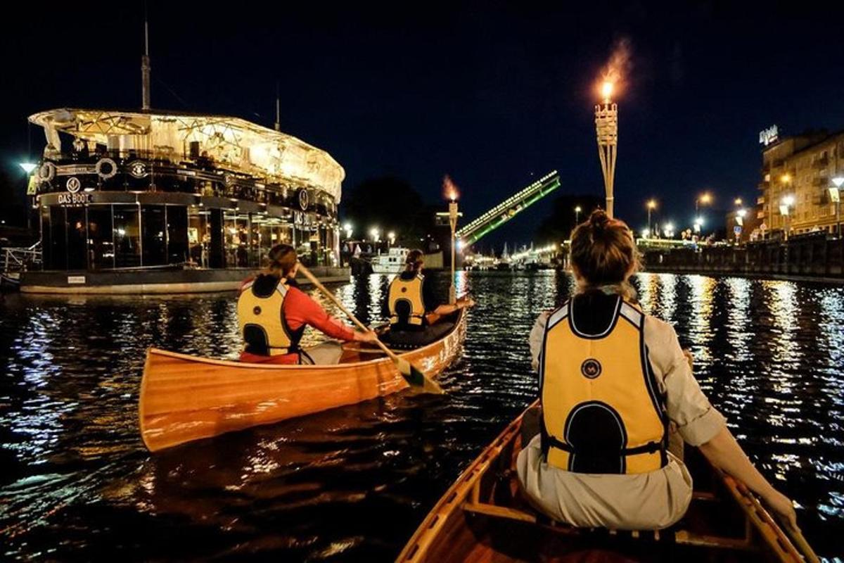 a group of people in canoes in the water at night